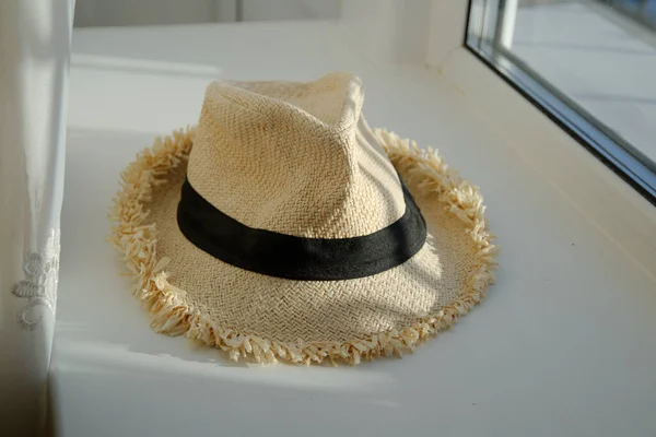 黒いリボンのついた白い夏の帽子は白い窓の上にあります 窓から光が 晴れた日 — ストック写真
