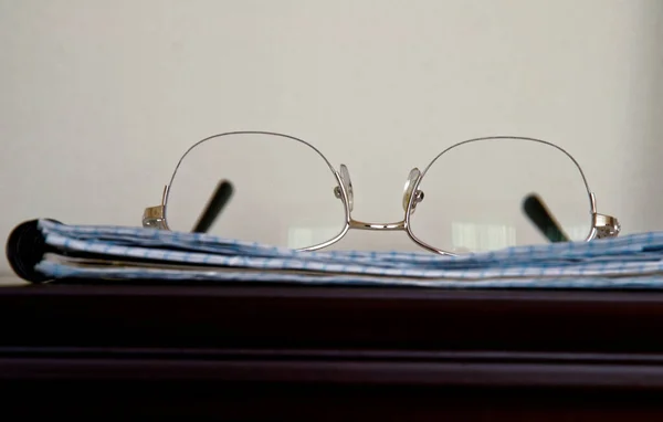 silver-rimmed glasses lie on a notebook. notebook in a cage.