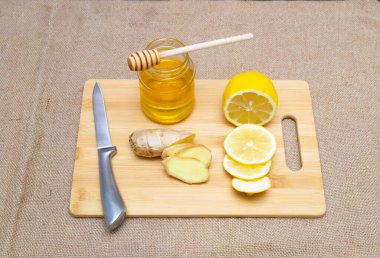 Dilimlenmiş zencefilli limon ve bal tahta üzerinde çuval bezi arka planda..