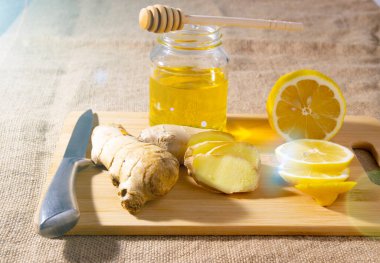 Dilimlenmiş zencefilli limon ve bal çuval bezi arka planında tahta bir tahta üzerinde. en üstteki görünüm.