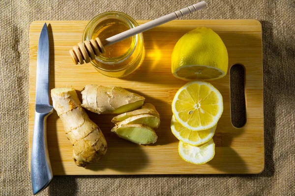 Gesneden plakjes gember citroen en honing op een houten plank op een zak achtergrond. bovenaanzicht. — Stockfoto