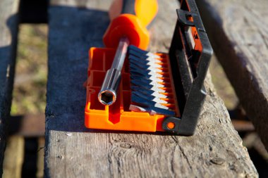 Değiştirilebilir parçaları olan turuncu bir tornavida sokaktaki ahşap bir palette yatıyor. Sokak tamiri konsepti. yakın plan.