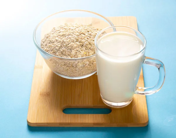 玻璃杯加牛奶 玻璃碗加燕麦片 蓝色底色 健康的早餐适当的食物 — 图库照片