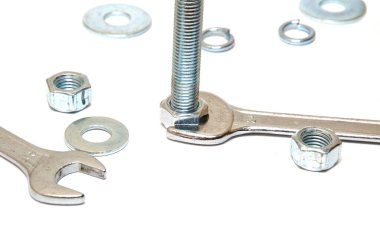 İngiliz anahtarı civatanın fındığını sıkılaştırır, çamaşır makineleri, somun ve cıvata yakınlarda yatar. Metal yapıların konsept onarımı, araba servisi, inşaat. İzole edilmiş beyaz arka plan. Boşluğu kopyala.