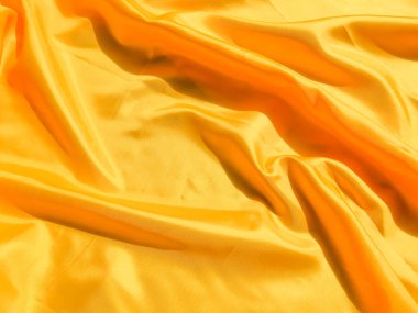 Arkaplanda dalgalar hareket eden parlak sarı ipek. Kopya alanı ile soyut tasarım