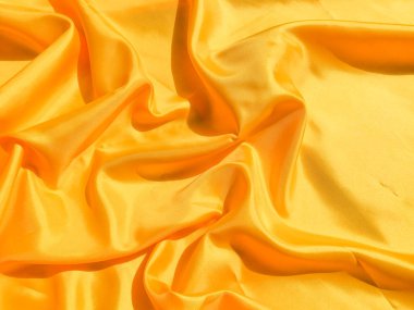 Arkaplanda dalgalar hareket eden parlak sarı ipek. Kopya alanı ile soyut tasarım