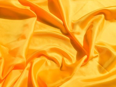 Arkaplanda dalgalar hareket eden parlak sarı ipek. Kopya alanı ile soyut tasarım