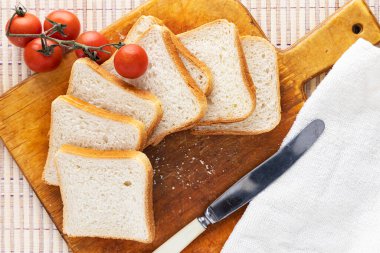 Taze ekmek, domates ve kesme tahtasında bir bıçak. Mutfak peçetesi. Sazlığın arkasında. Yukarıdan görüntüle
