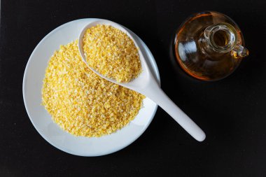 Siyah arka planda beyaz bir tabakta mısır gevreği. Beyaz bir tabakta anında mısır gevreği. Mısır yağı. A vitamini konsepti. Üst görünüm.