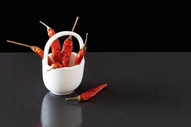 Beyaz, küçük bir sepetin içinde kurutulmuş kırmızı biber. Koyu bir arka planda kurutulmuş kırmızı biber kabukları. - Yakın çekim. Üst görünüm