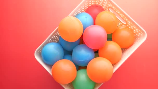 Vista superior de la bola de plástico de colores sobre fondo rojo — Vídeos de Stock