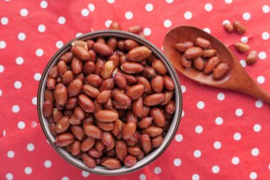 Close up of peanut in a bowl on red background