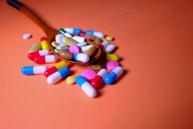 closeup of colorful pills on spoon on color background 