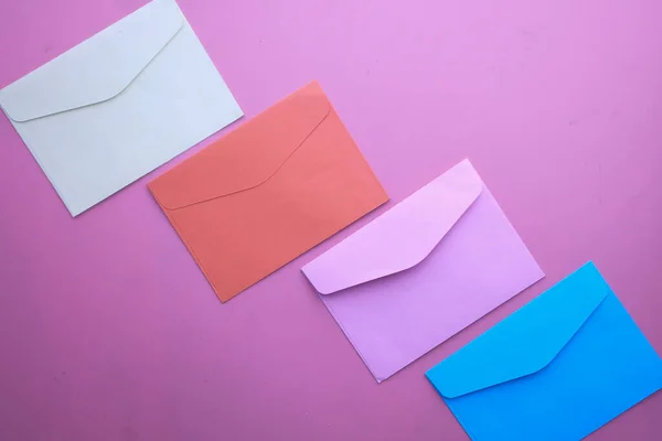 Vista superior de envelopes coloridos sobre fundo rosa — Fotografia de Stock