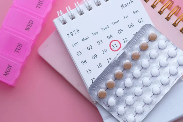 Píldora anticonceptiva y fecha de calendario con caja de píldora en la mesa — Foto de Stock
