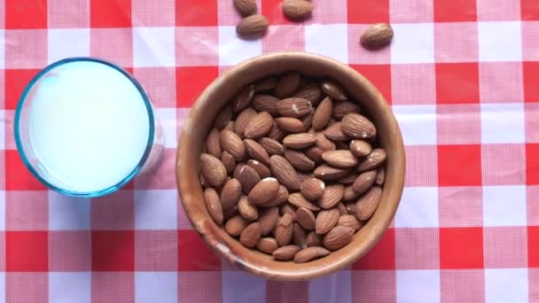 Bovenaanzicht van amandel in een kom en melk op tafel — Stockvideo
