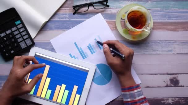 A pénzügyi adatok és a digitális táblagép elemzése az irodai asztalon — Stock videók