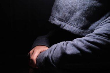 Kapüşonlu üzgün adam gece aşağı bakıyor. 