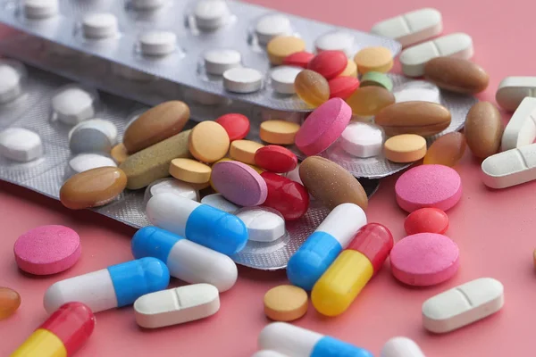 Pillole colorate e capsula su sfondo di colore, primo piano — Foto Stock