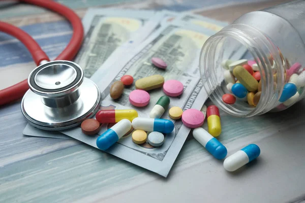 Close up of pill, cash and stethoscope on table — Stok fotoğraf