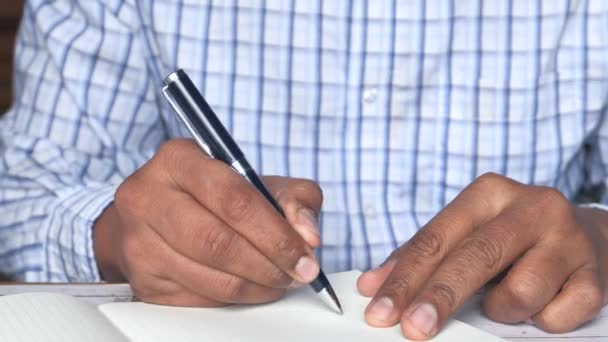 Primer plano de la escritura manual del hombre en papel en el escritorio de la oficina — Vídeos de Stock