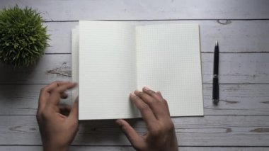 Not defterinin sayfasını çeviren adamın üst görünümü 
