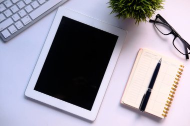 Masadaki dijital tablet, not defteri ve klavyenin üst görünümü 