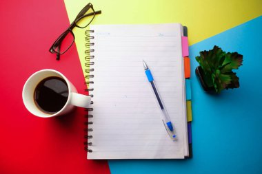 top view of notepad and coffee on color background 