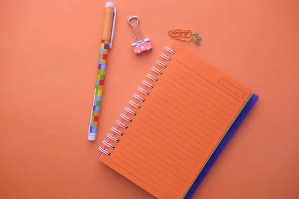 Vista dall'alto di blocco note e penna su sfondo arancione — Foto Stock