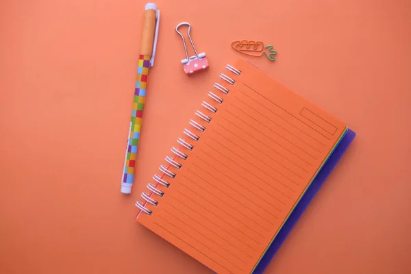 Vista superior del bloc de notas y la pluma sobre fondo naranja — Foto de Stock