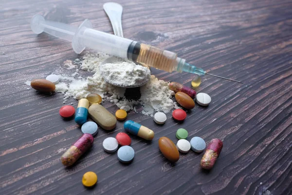 Концепция злоупотребления наркотиками с помощью таблеток и шприца — стоковое фото