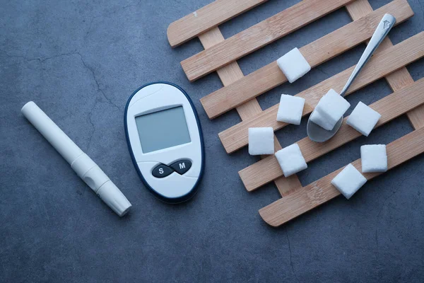 Lårvinkelvy av diabetiska mätverktyg och sockerkub på bordet — Stockfoto