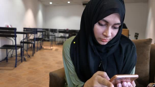 Primer plano de las mujeres musulmanas utilizan el teléfono inteligente en la cafetería — Vídeo de stock