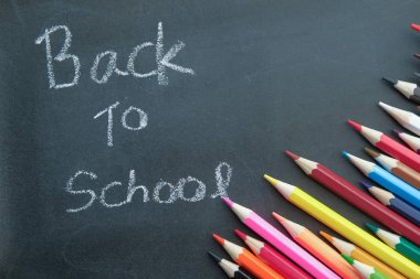 Kara tahtanın üzerindeki renkli kalemlerle okula geri dön 