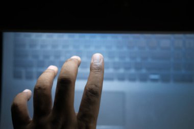 top view of hooded hacker sealing data from laptop 