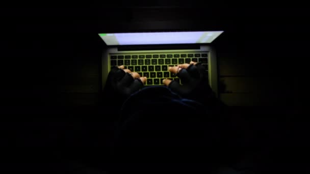 Hooded hacker sealing data from laptop at night — Stock Video