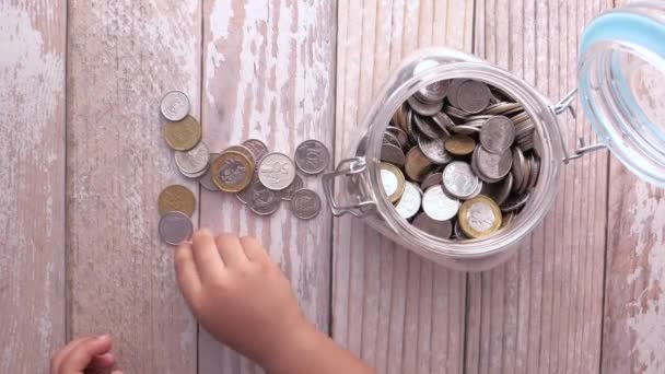 瓶の中の子供の手の貯蓄コインのトップビュー — ストック動画