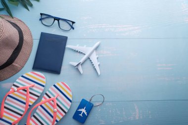 Mavi arka plan, şapka, pasaport, cep telefonu, güneş gözlüğü üzerindeki turist aksesuarlarının yüksek açılı görünümü.