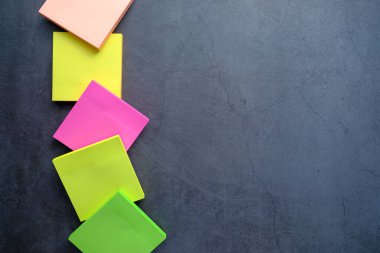 Siyah tabloda kopyalama alanı olan renkli yapışkan notların üst görünümü 