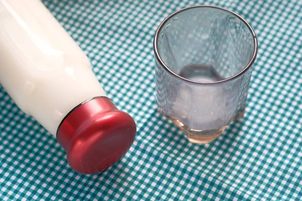 Fechar de vidro vazio e garrafa de leite na mesa — Fotografia de Stock