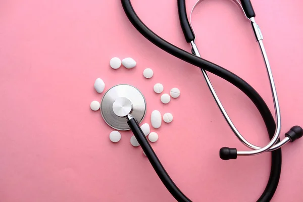 Close up of white pills and stethoscope on pink background — Stock Photo, Image