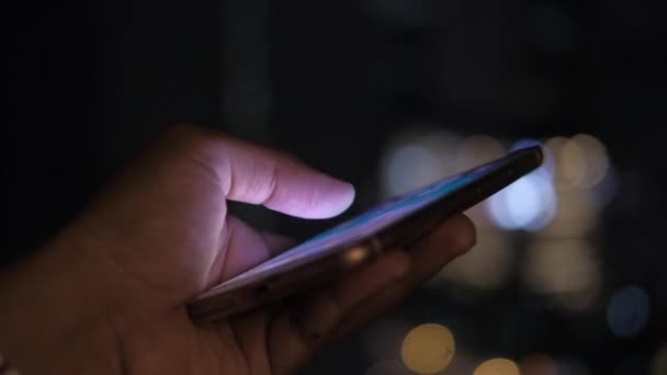 Primo piano dell'uomo mano utilizzare smart phone di notte in città — Video Stock