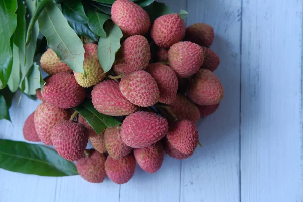 Litchi frais avec feuilles sur fond bois Fruits tropicaux — Photo