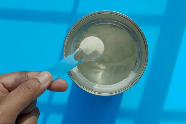 Leche en polvo para bebés en cuchara sobre fondo de color — Foto de Stock