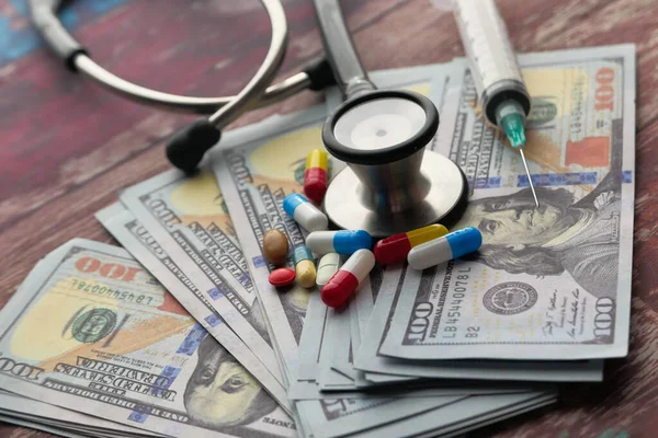 Крупним планом готівку, таблетки і стетоскоп на столі — стокове фото