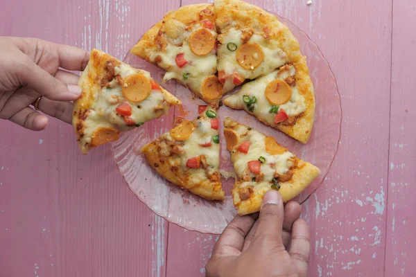 Mani che prendono fette di pizza dal piatto, vista dall'alto — Foto Stock