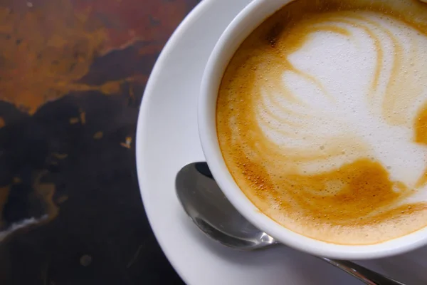 Close up de café tarde com creme em uma xícara na mesa — Fotografia de Stock