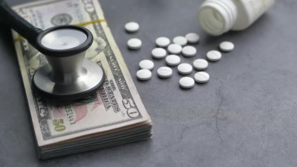 Gros plan sur l'argent comptant, la pilule et le stéthoscope sur la table — Video