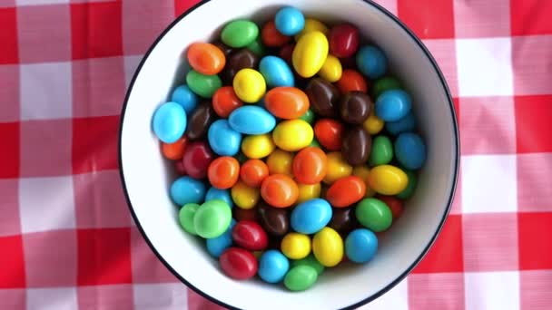 Bovenaanzicht van kleur chocolade in een kom op tafel — Stockvideo
