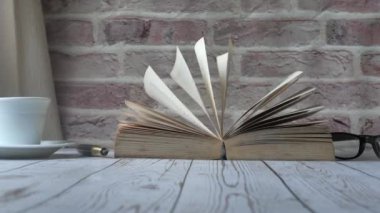 close up of open book and tea cup on table 
